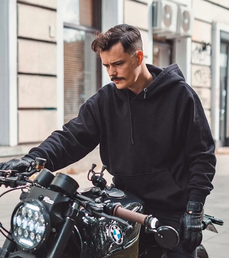 Portrait of Ludovic in a black hoodie sitting on his black BMW K1100 brat on a Warsaw street