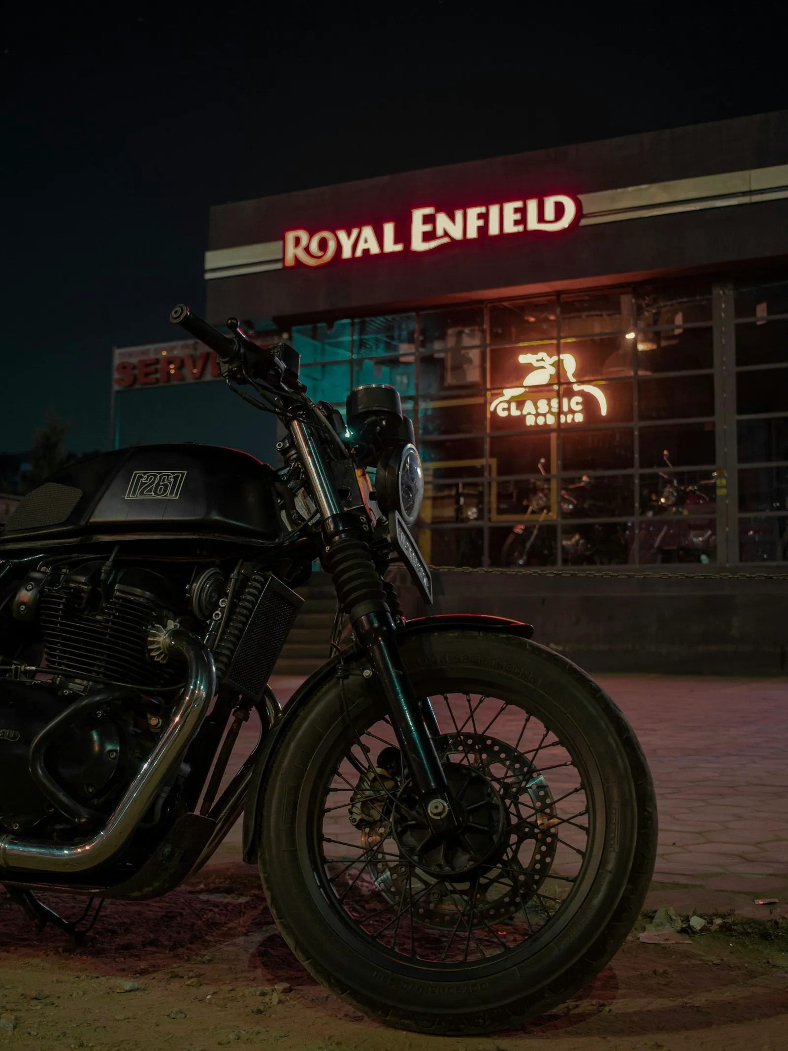 Cafe racer parked outside a bar beneath a red neon sign