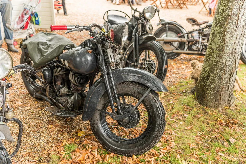 Vintage hardtail Harley-Davidsons with springer forks parked in the rain at a motorcycle show
