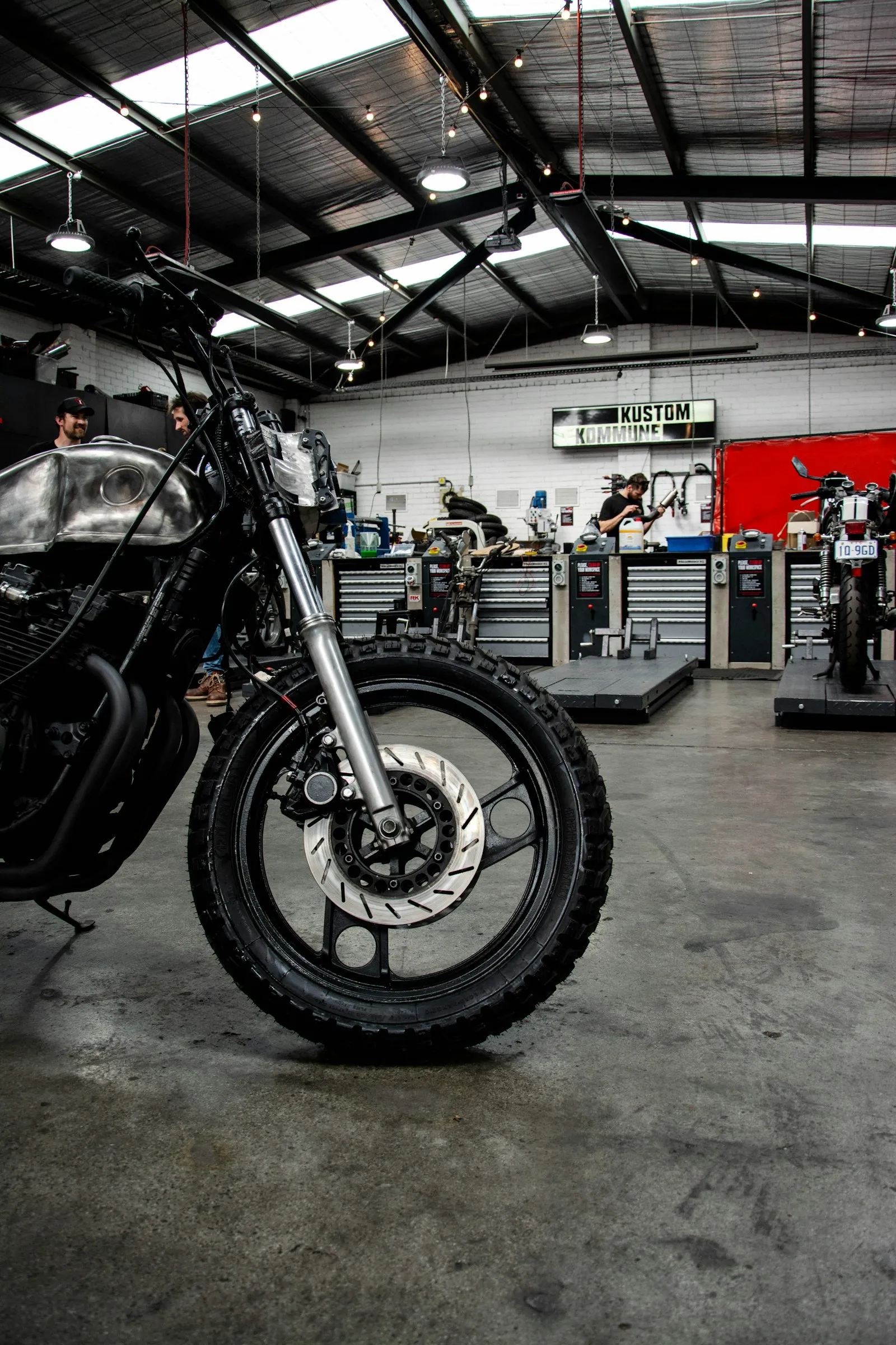 Scrambler motorcycle with knobbly tyres parked inside a workshop