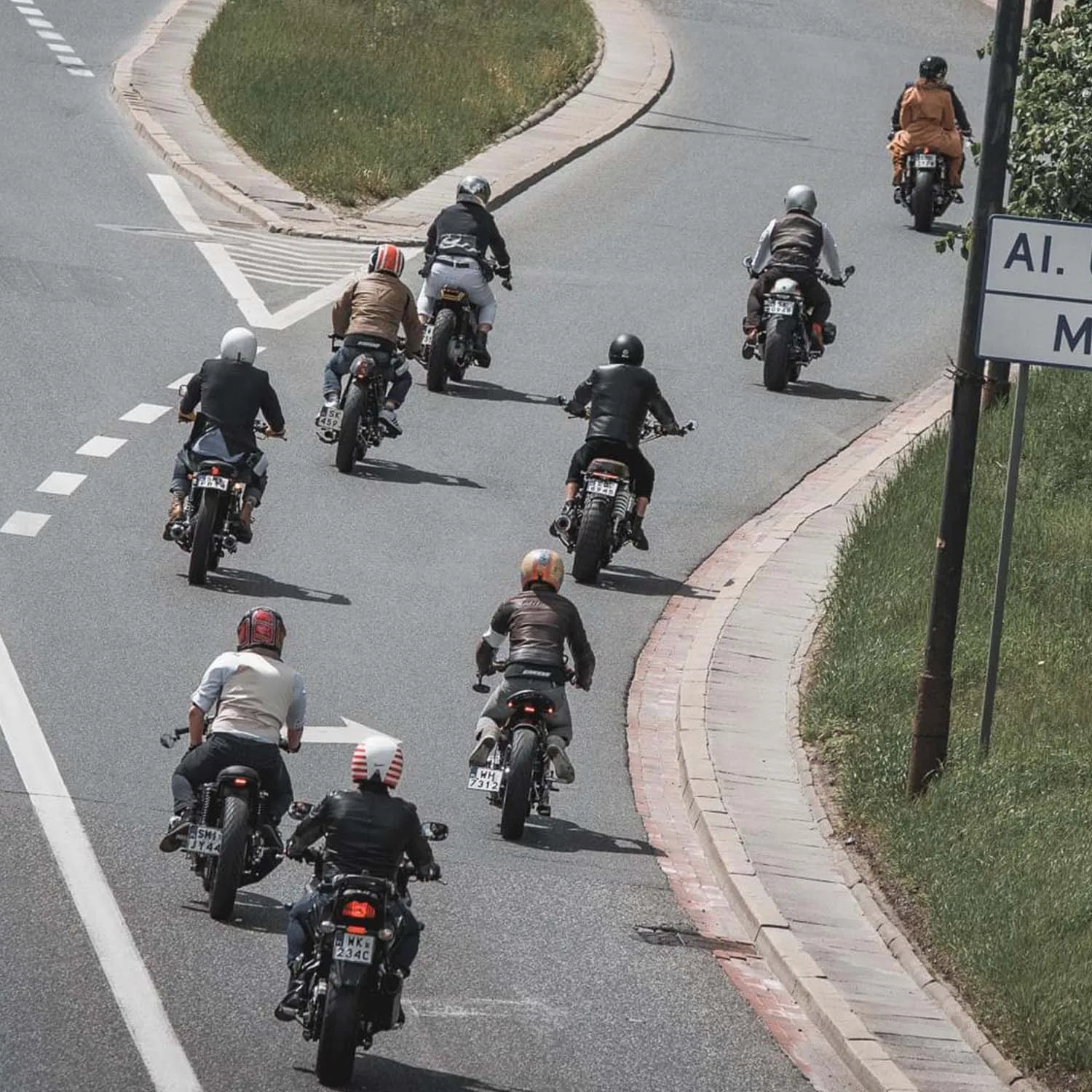 A pack of custom motorcycles seen from above sweeping through a curve on a Warsaw road
